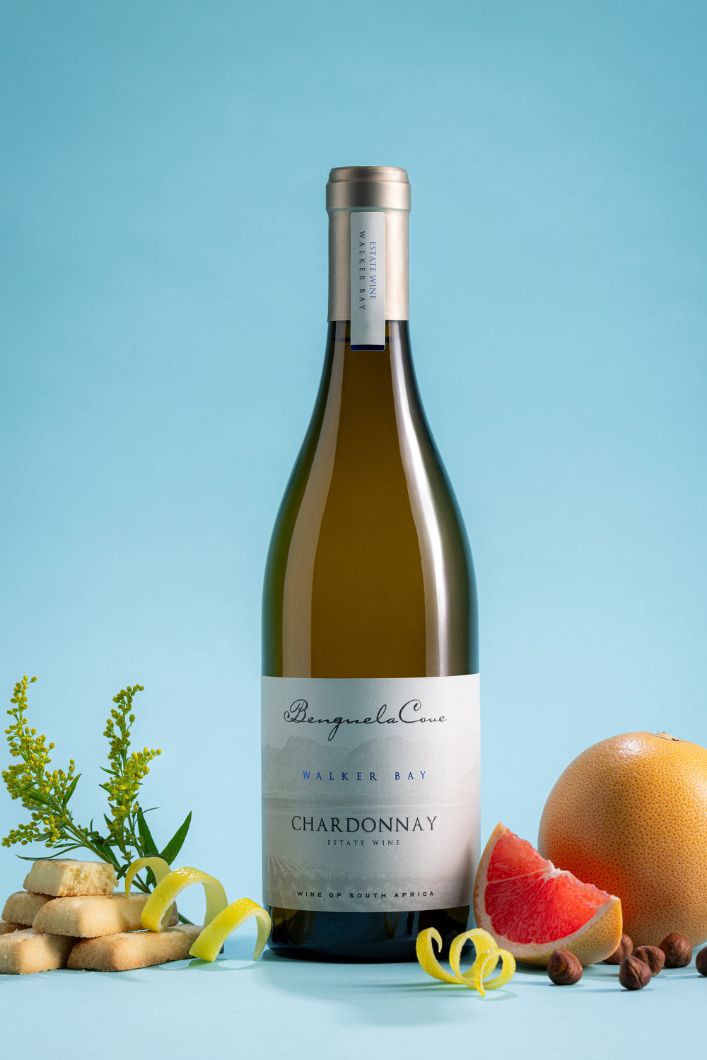 Bottle of Chardonnay wine with fruits and cheese on a blue background
