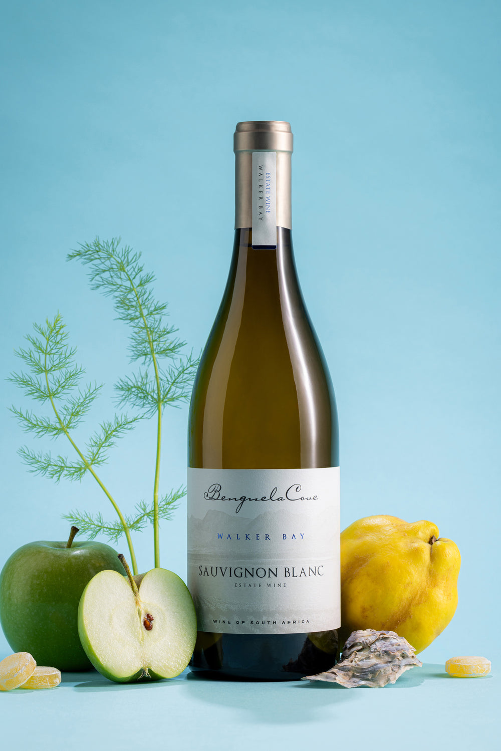 Bottle of Sauvignon Blanc wine with apples and a quince on a blue background