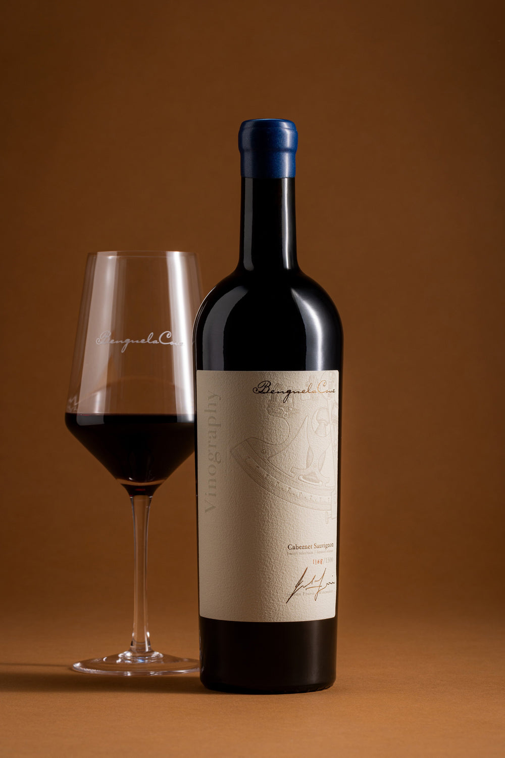 Bottle and glass of red wine with a brown background