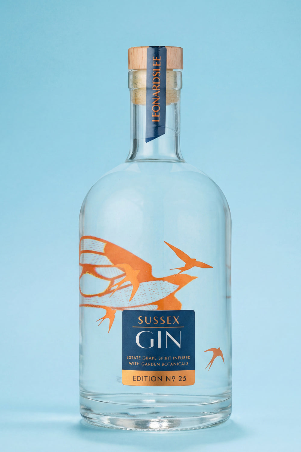 Bottle of Sussex Gin with a blue label and orange design on a light blue background